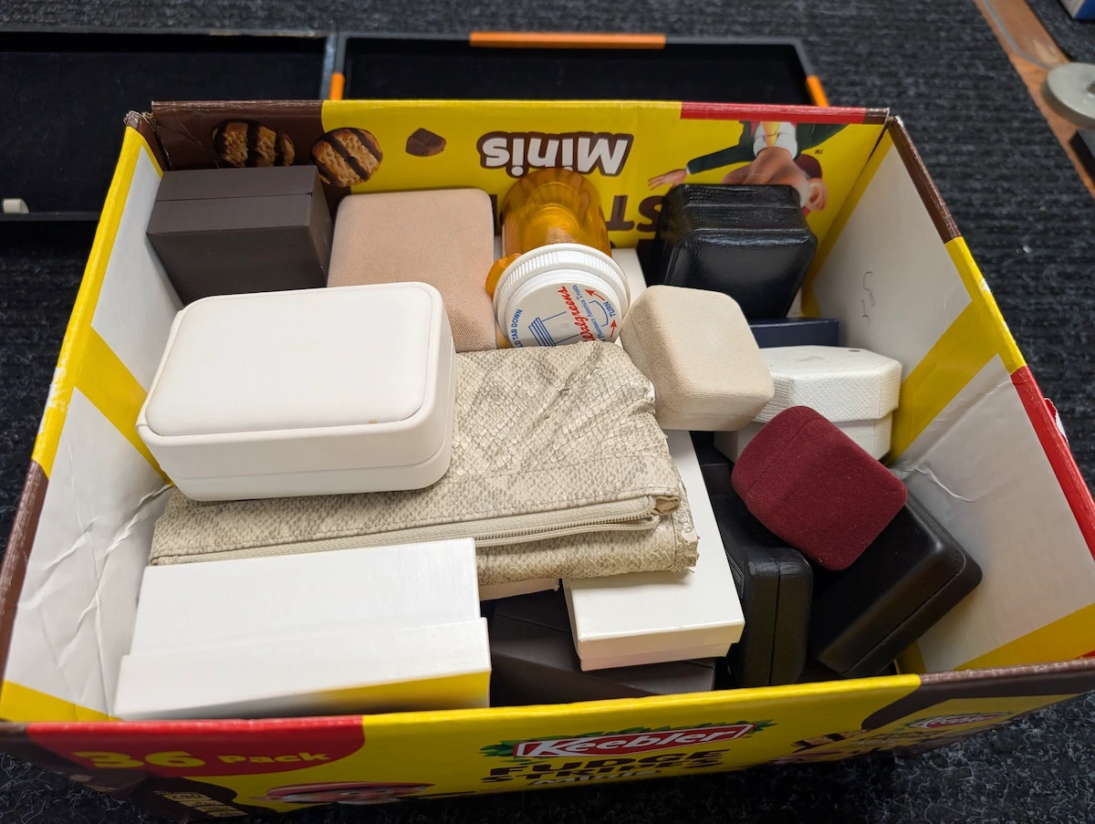 Box of coin holders, jewelry boxes, and estate items brought to Oakton Coins & Collectibles for evaluation.